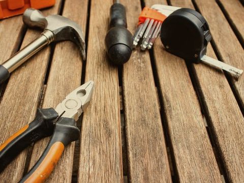 A hammer, pliers, tape measure and hex keys on a slatted timber table