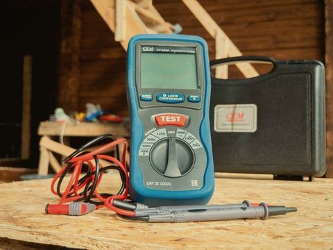 An insulation tester and test leads on a timber workbench